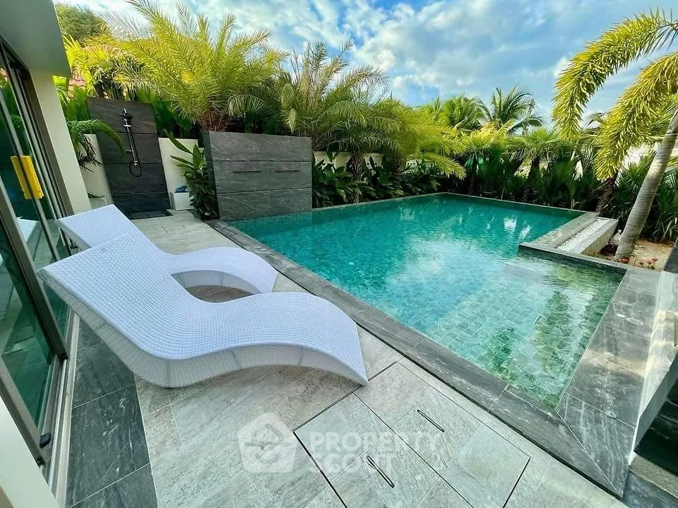 Luxurious private pool with tropical landscaping and modern lounge chairs