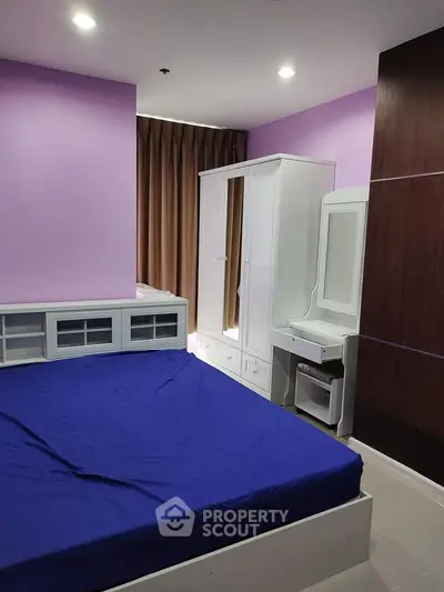 Modern bedroom with purple walls, white furniture, and blue bedding in a stylish apartment.