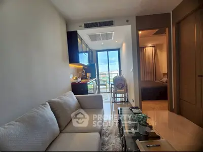 Modern living room with cozy sofa, open kitchen, and balcony view in stylish apartment.
