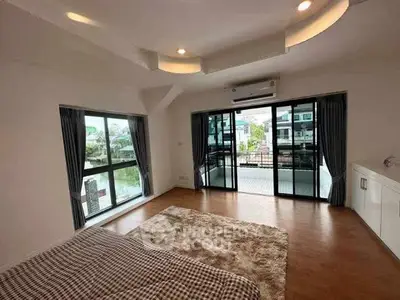 Spacious bedroom with large windows and balcony access in modern home.
