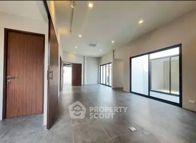 Spacious modern living room with large windows and sleek tile flooring.