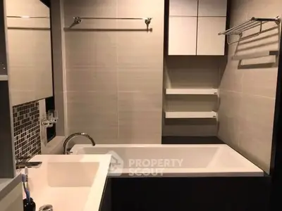 Modern bathroom with sleek design and bathtub, featuring elegant fixtures and ample storage space.