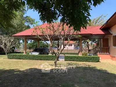 Charming single-story home with red roof and lush garden, featuring a carport and inviting outdoor space.