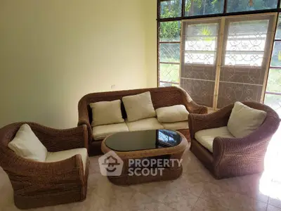 Cozy living room with wicker furniture and glass coffee table, perfect for relaxation.