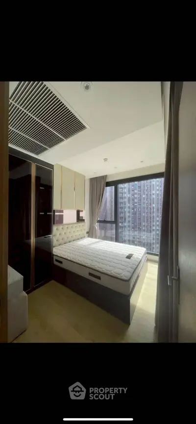 Modern bedroom with large window and city view, featuring sleek design and ample natural light.