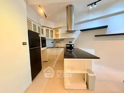 Modern kitchen with sleek black countertops and stainless steel appliances in a stylish open layout.