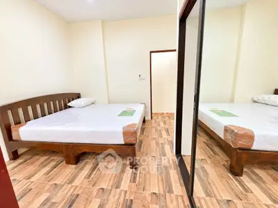 Cozy bedroom with wooden bed frame and mirrored closet in modern apartment.