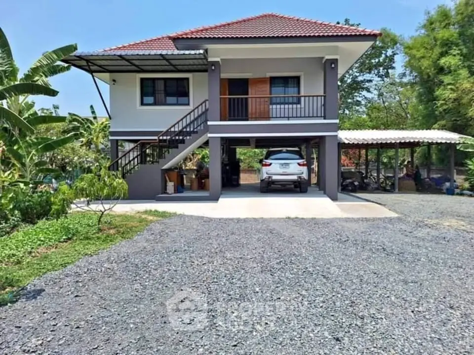 Charming elevated house with carport and lush garden surroundings.