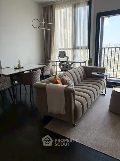 Modern living room with elegant sofa and dining area, featuring large windows with city view.