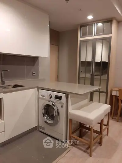 Modern kitchen with sleek white cabinets and built-in washing machine