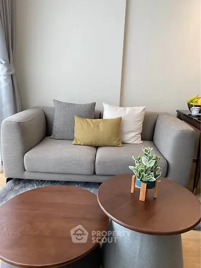 Stylish modern living room with cozy gray sofa and chic wooden coffee tables.
