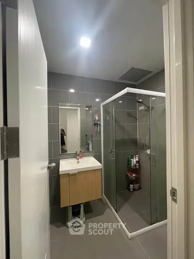 Modern bathroom with glass shower and sleek vanity in contemporary apartment.