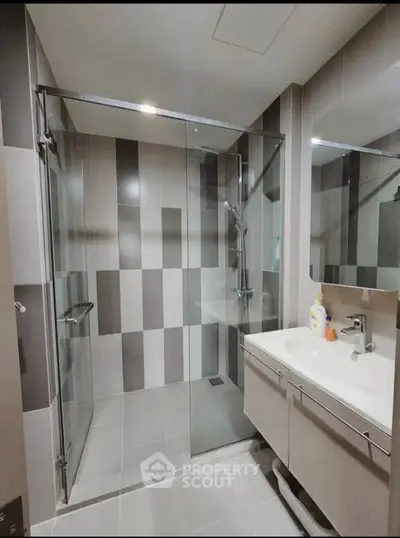 Modern bathroom with glass shower and sleek vanity in stylish apartment.