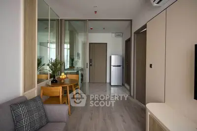 Modern living room with sleek design and compact kitchen area, featuring stylish furniture and mirrored walls.
