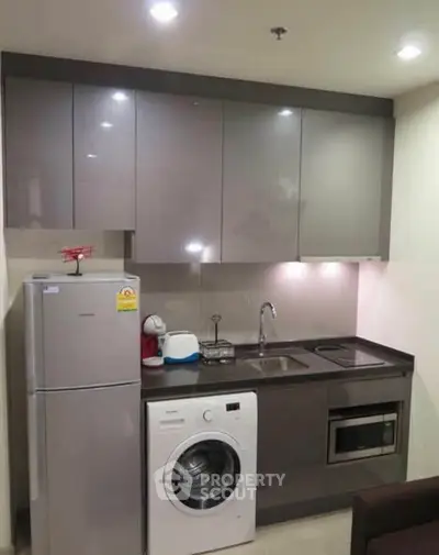 Modern kitchen with sleek cabinets, washing machine, fridge, and built-in microwave.