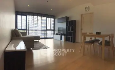 Spacious modern living room with large windows and stylish furniture in a high-rise apartment.