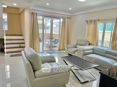 Spacious living room with modern furniture and large windows opening to a patio.