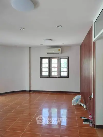 Spacious empty room with wooden flooring and large windows, perfect for customization.