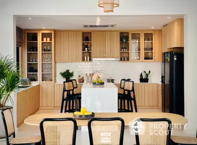 Elegant modern kitchen with natural wood finishes, featuring a spacious dining area, high-end appliances, and ample storage, perfect for entertaining.