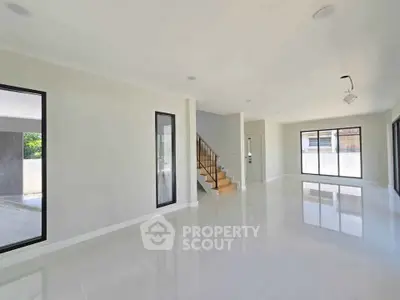Spacious modern living room with large windows and sleek staircase