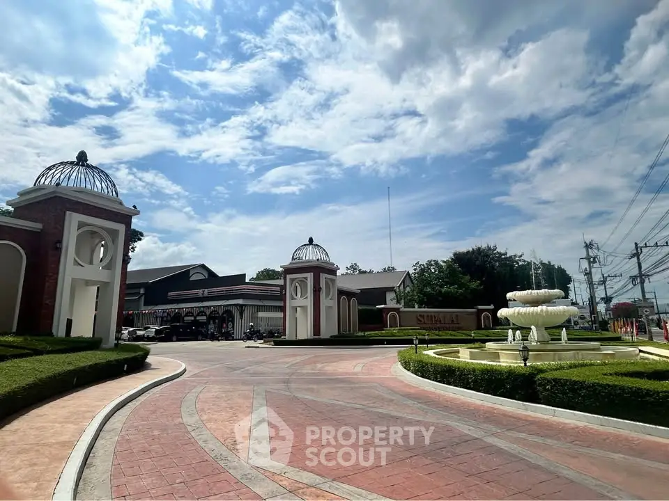 Elegant entrance with fountain and landscaped gardens under a bright sky, showcasing luxury real estate.