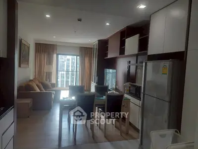 Modern open-plan living room with kitchen and dining area, featuring large windows and stylish furniture.