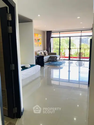 Spacious living room with large windows and balcony view, modern decor and natural light.