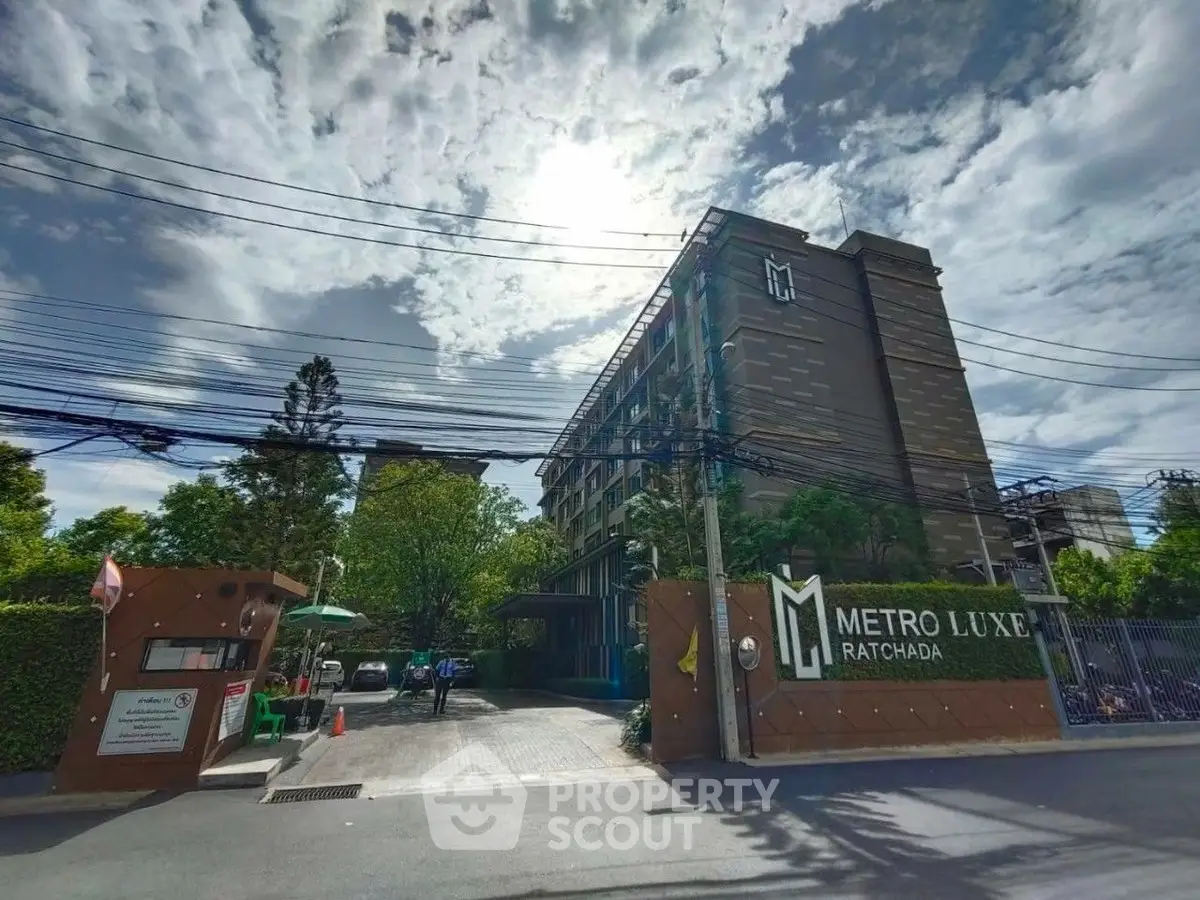 Modern condominium building with lush greenery at Metro Luxe Ratchada.