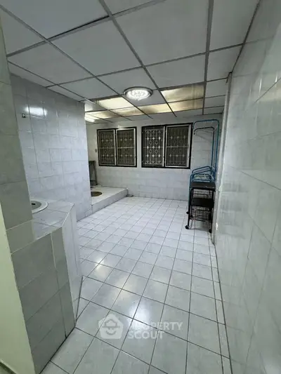 Spacious tiled bathroom with large windows and ample natural light.