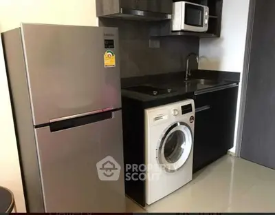 Modern kitchen with sleek appliances including fridge, washing machine, and microwave in compact layout.