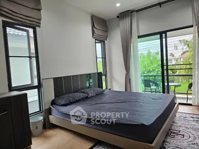 Spacious bedroom with large windows and balcony overlooking lush greenery, perfect for relaxation.