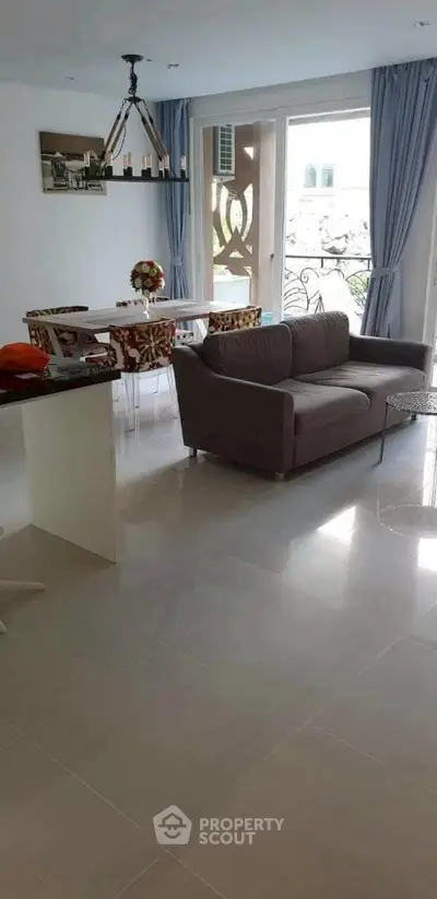 Modern living room with elegant decor and natural light, featuring a cozy sofa and stylish dining area.