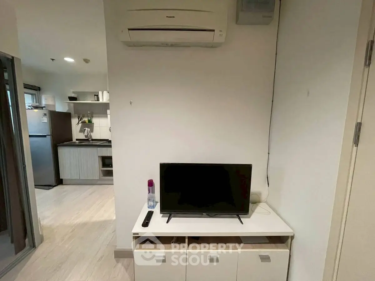 Modern apartment interior with compact kitchen and TV area