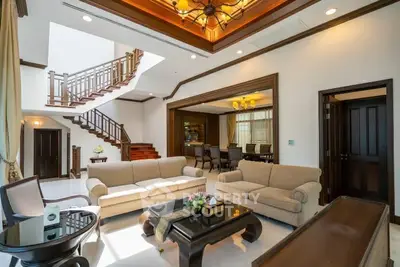 Luxurious living room with elegant staircase and stylish furniture in a spacious open layout.
