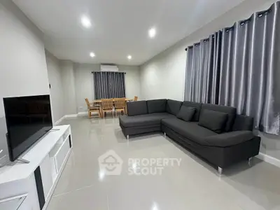 Spacious modern living room with sleek black sofa and dining area