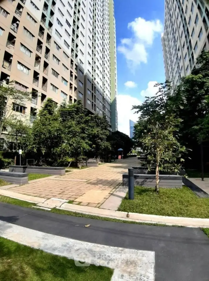 Modern high-rise residential buildings with lush green landscaping and paved walkways.
