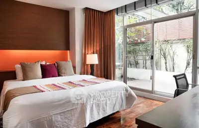 Luxurious bedroom with large windows and garden view, featuring elegant decor and cozy ambiance.