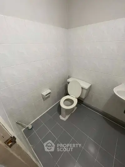 Simple bathroom with tiled walls and floor, featuring a toilet and sink.