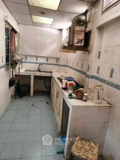 Compact kitchen with tiled walls and ceiling, featuring basic appliances and storage.