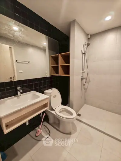 Modern bathroom with sleek fixtures and spacious shower area in a contemporary apartment.