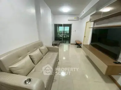 Modern living room with sleek furniture and large TV, featuring a bright and airy atmosphere.