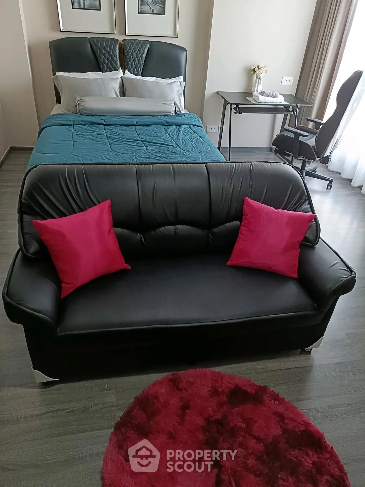 Modern bedroom with stylish black sofa and vibrant red accents, perfect for urban living.