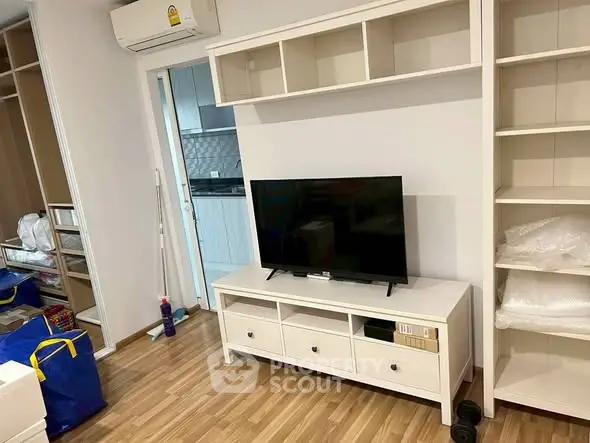 Modern living room with sleek TV stand and open shelving, adjacent to a stylish kitchen.