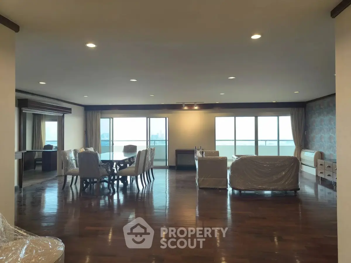 Spacious living room with large windows and elegant dining area, offering a luxurious open layout and stunning views.