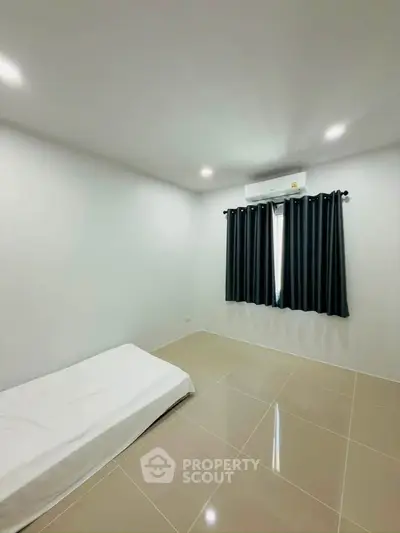 Minimalist bedroom with single bed and air conditioning, ideal for a cozy living space.