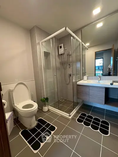 Modern bathroom with glass shower and sleek vanity in contemporary apartment.