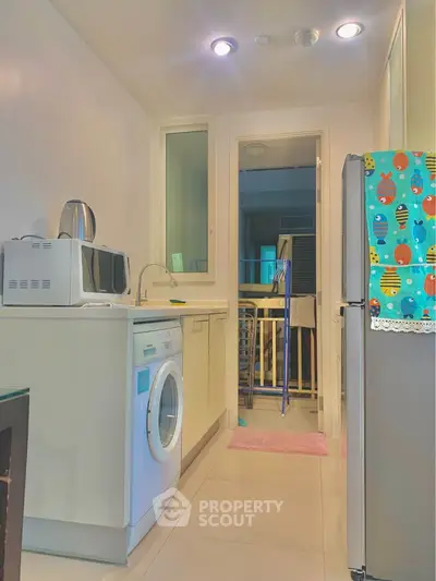 Compact kitchen with washing machine and microwave, bright and functional space.