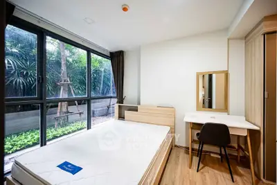 Modern bedroom with large windows and garden view, featuring a minimalist design and wooden flooring.