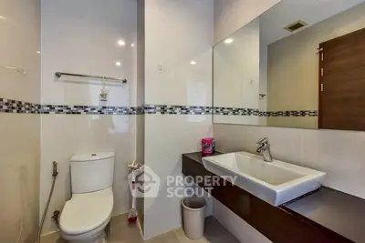 Modern bathroom with sleek fixtures and large mirror in contemporary apartment.