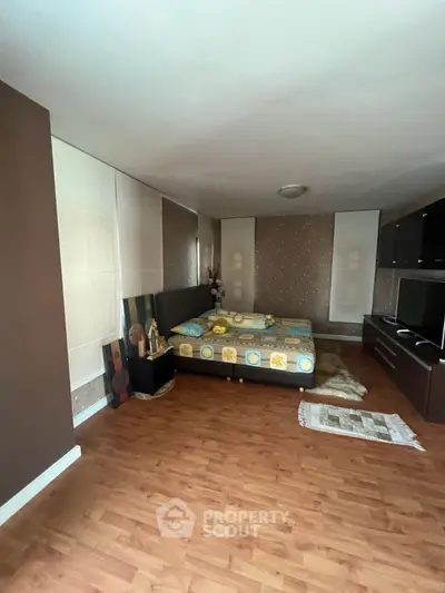 Spacious bedroom with wooden flooring and modern decor, ideal for comfort and relaxation.
